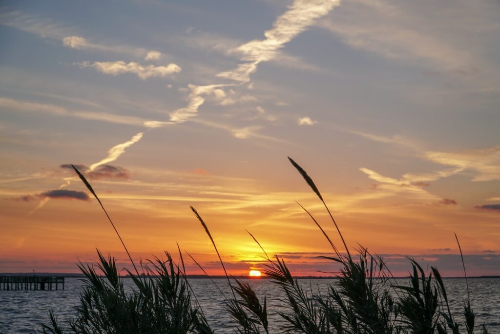 A sunset with the sun setting over water.